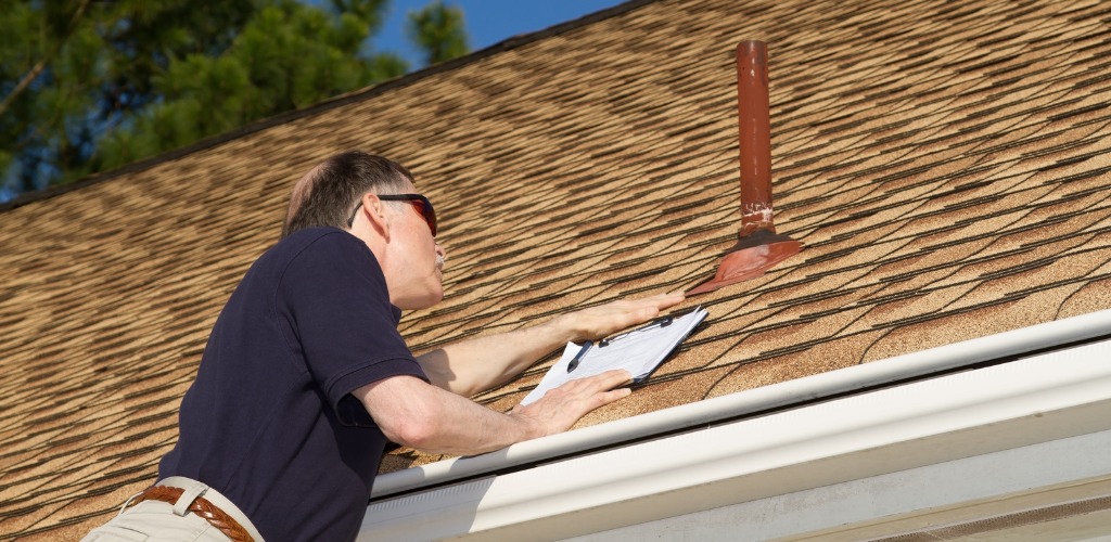 an inspector checking flashing around a roof vent pipe