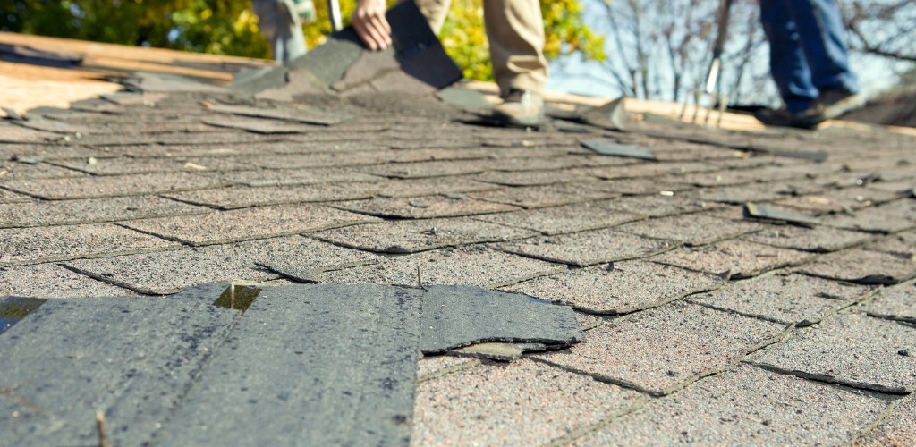 Workers tearing off and removing old asphalt shingles